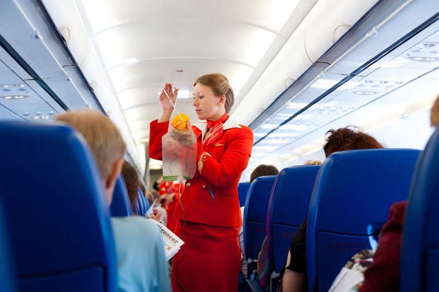 Female flight attendant demonstrating use of oxygen mask