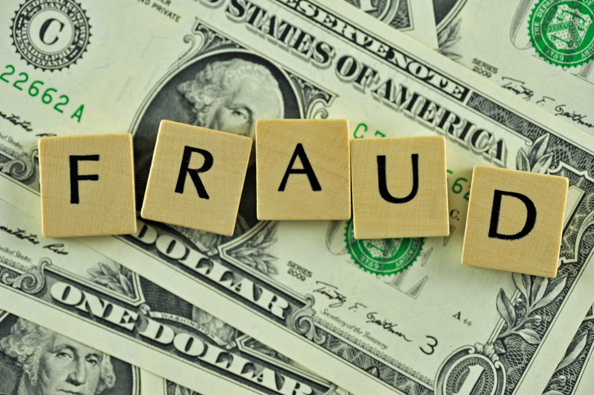 Word fraud in letters on background of dollar banknotes
