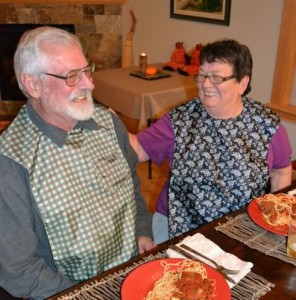 senior couple eating dinner, wearing tidy top apron