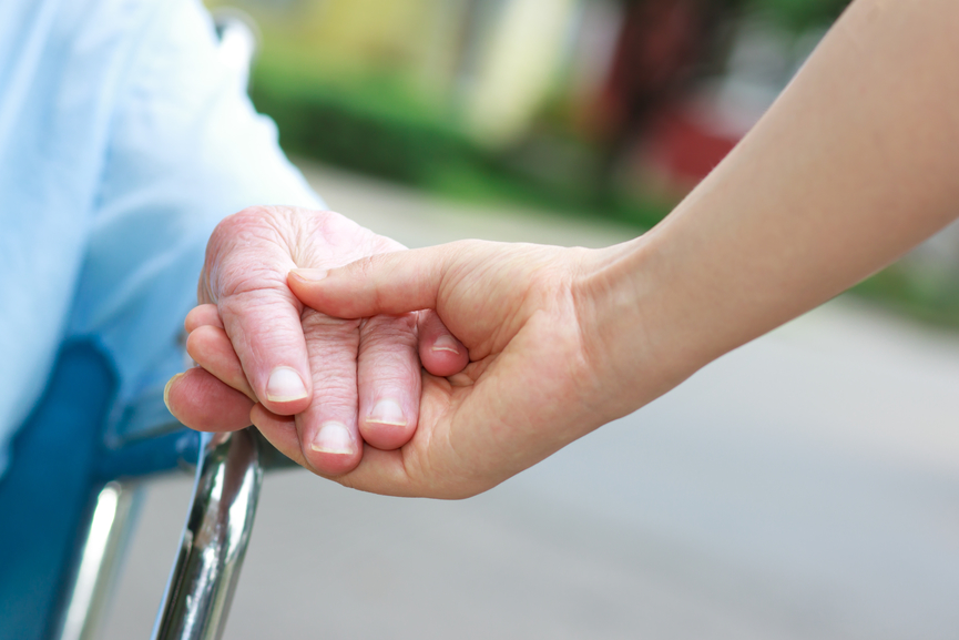 Senior women in wheelchair holding hands with caretaker
