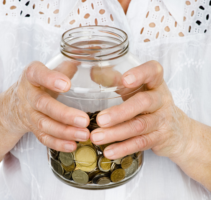 a senior woman holding a jar of coins