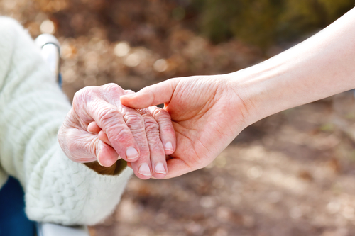 Senior Lady Holding Hands with Younger Caregiver