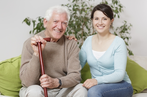 Smiling senior man holding cane and sitting with grandaughter