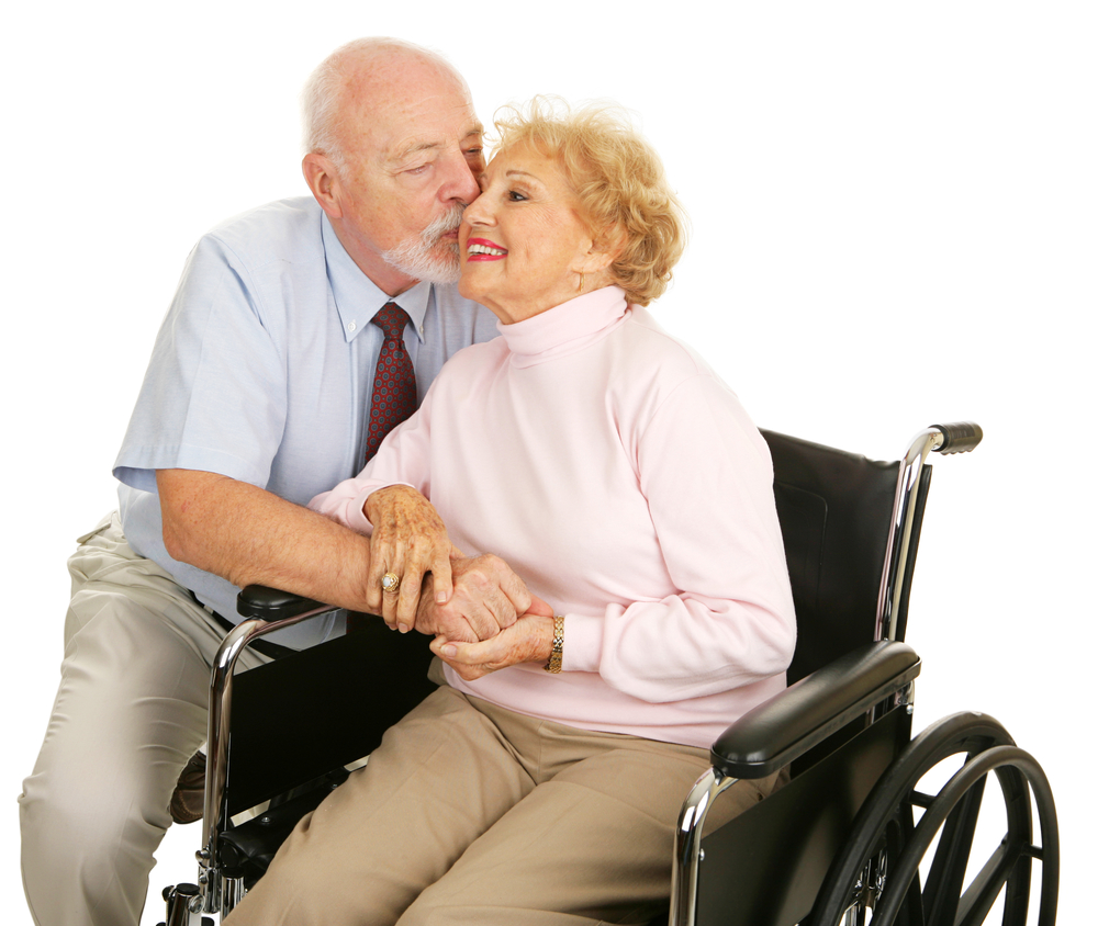 Affectionate senior husband giving his disabled wife a kiss on the cheek. Isolated on white.