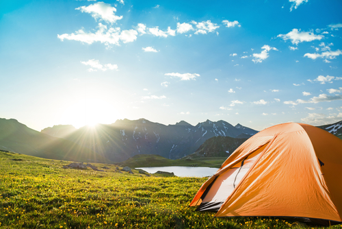 tourist tent camping in mountains by a lake during daylight