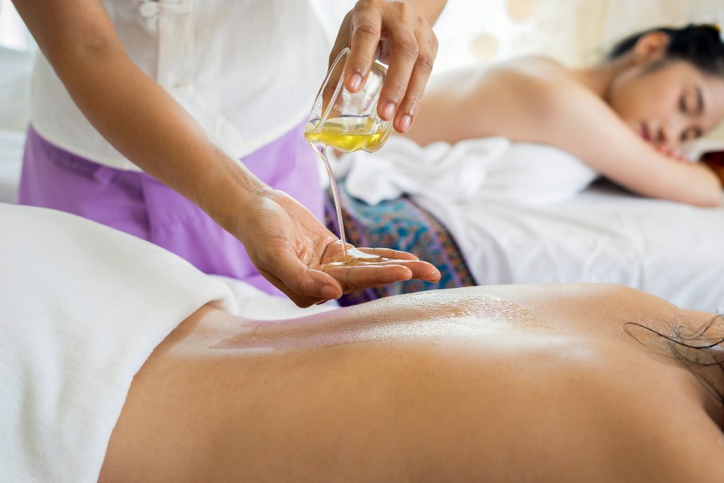 Woman pouring massage oil into her hand.