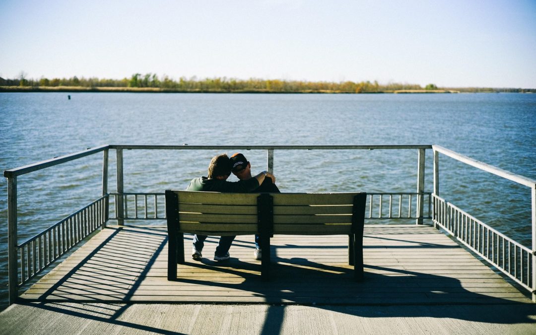 couple sitting on bench by the water
