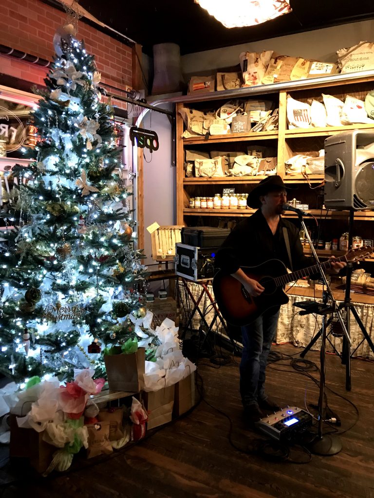 A singer with guitar performing by a Christmas tree