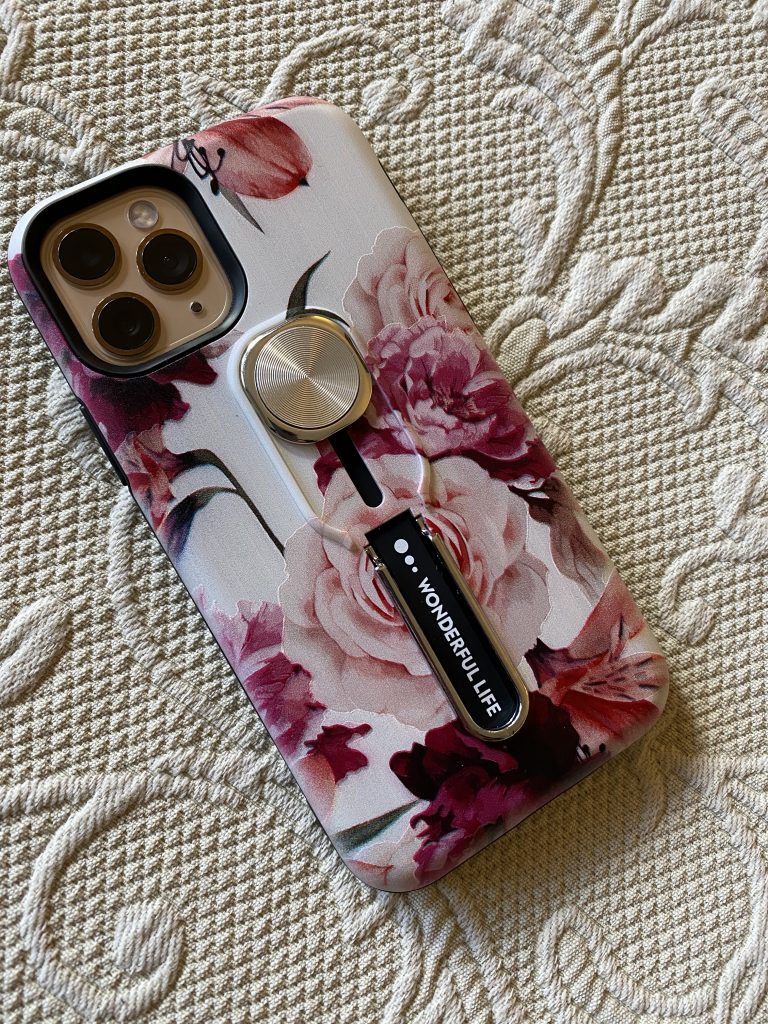 IPhone cae with burgundy and pink flowers, as well as a rubber finger strap for holding. 