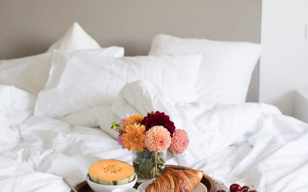 Breakfast on the bedspread of a bed with fluffy pillows