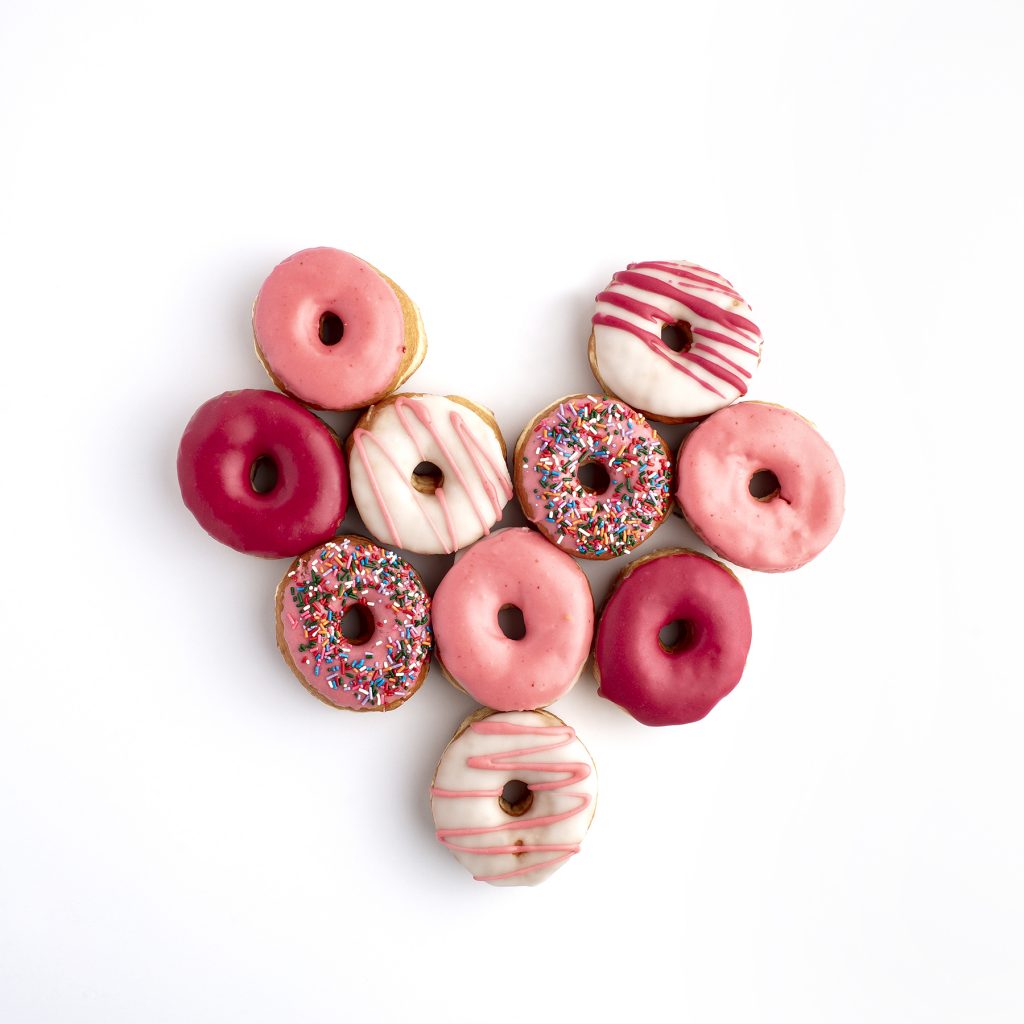 a plate of frosted donuts shaped like a heart