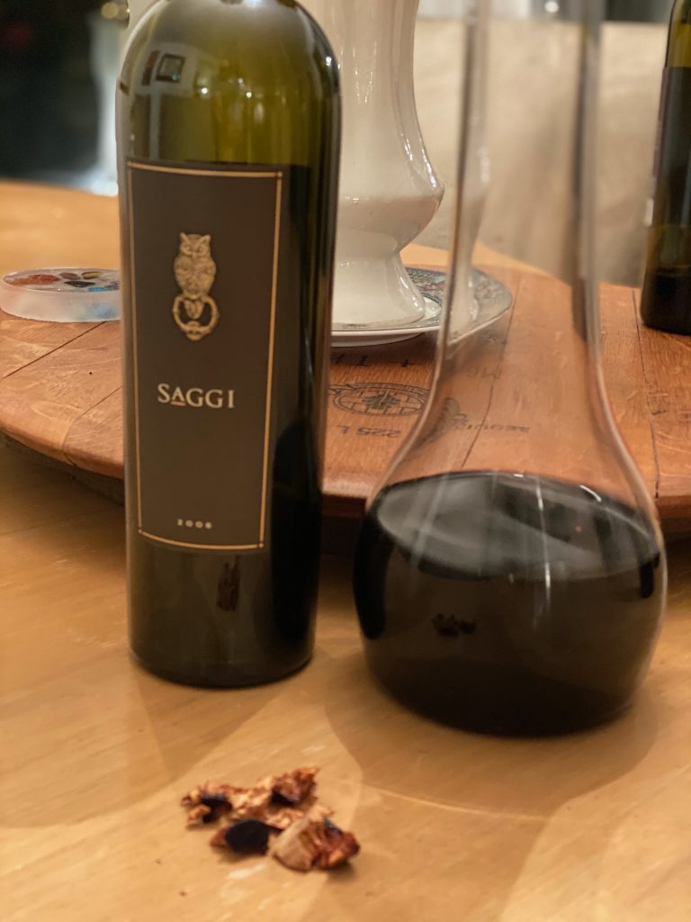 The bottle of Saggi next to a decanter with pieces of cork in front