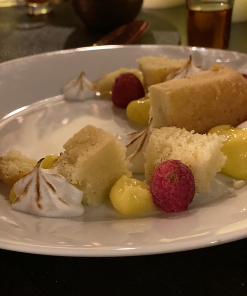Dessert of Summer citrus cake pieces, toasted meringue pieces, raspberries and lemon curd shaped into a half moon