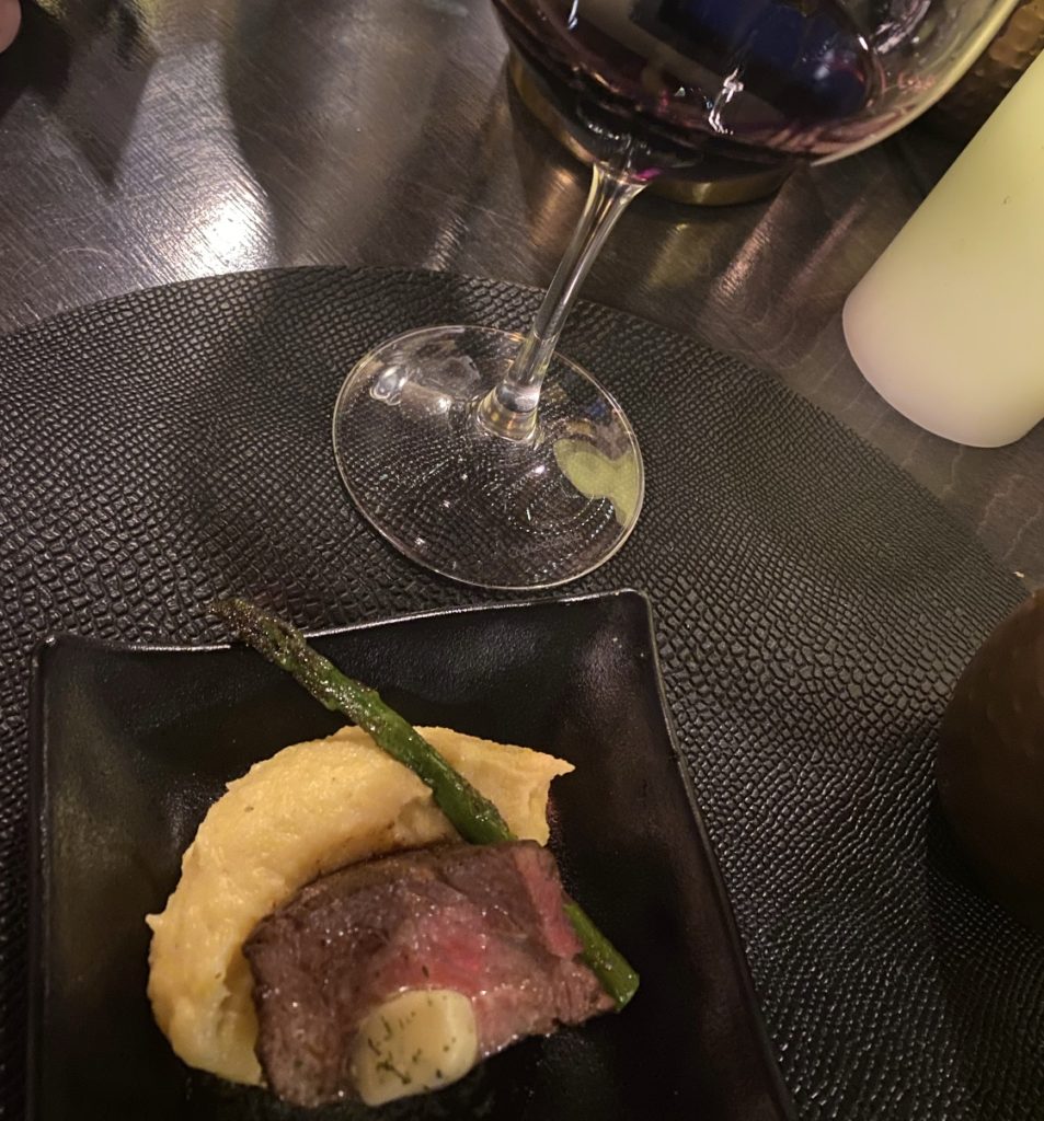 Steak alongside grits topped with an asparagus spear