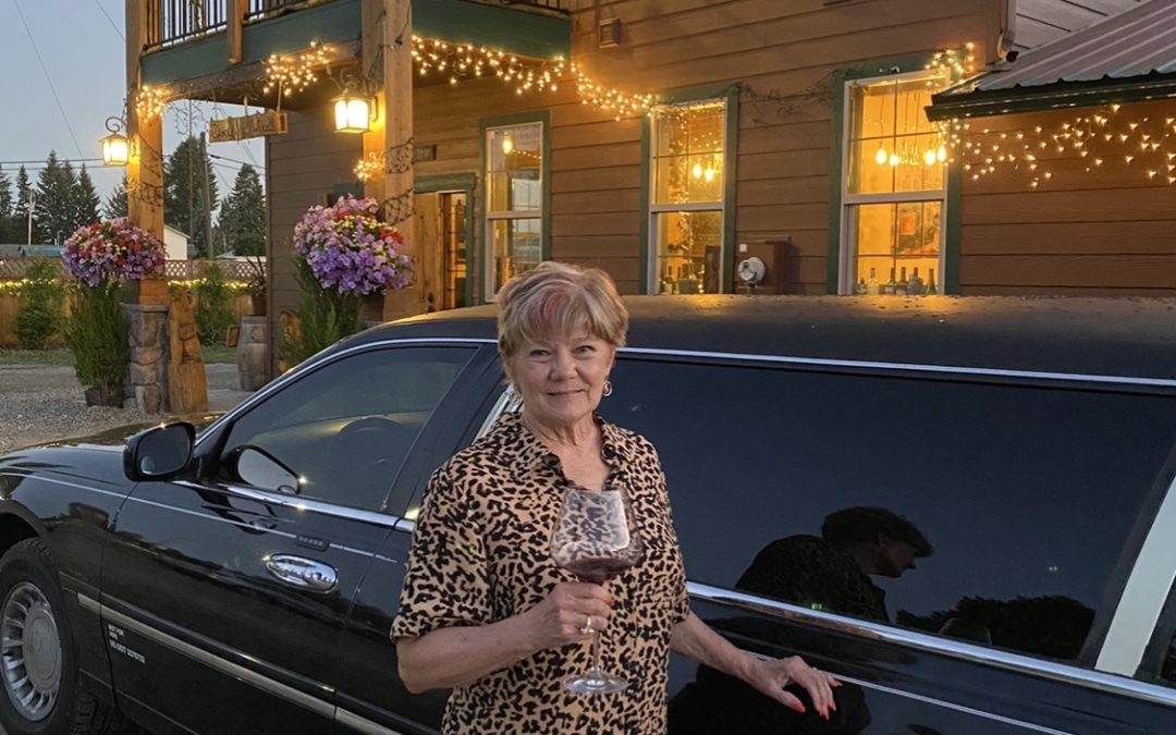 Shelley outside of the restaurant standing by the limo with a glass of red wine in her hand