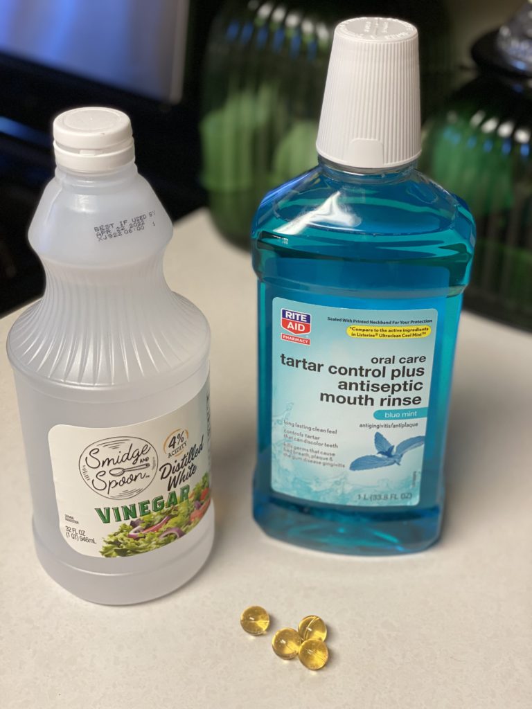 a bottle of white vinegar, a bottle of blue generic listerine and 3 bath oil beads