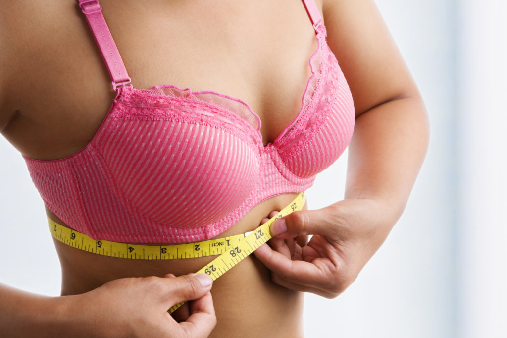 woman measuring her band size with yellow measuring tape