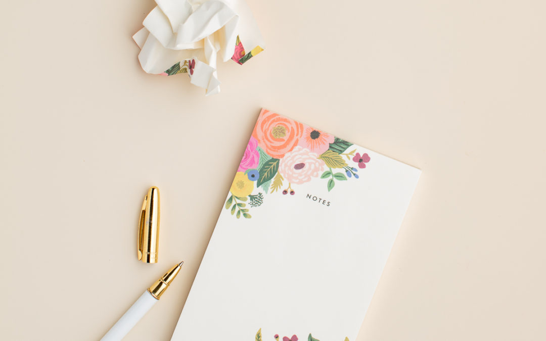 flat lay of a flower embellished notepad and a pen to use for your brain dump