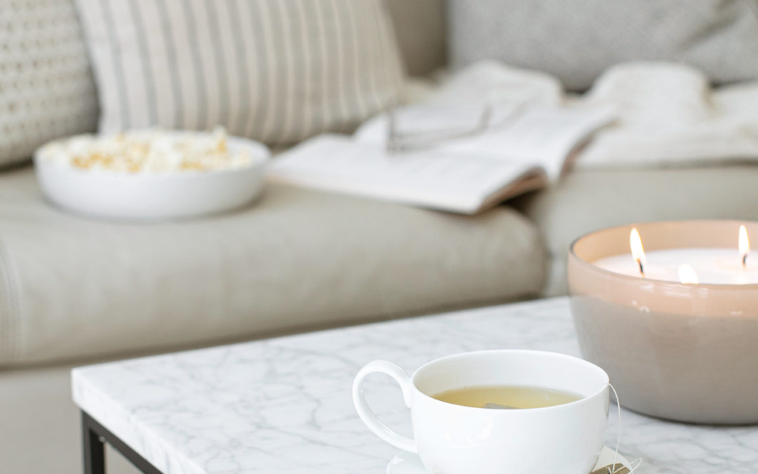 a cozy fall setting with coffee, candle, popcorn and throw