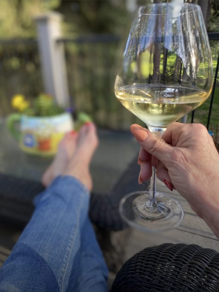 Shelley on the deck, with her feet elevated on the coffee table,holding a glass of wine while her feet are resting on the table