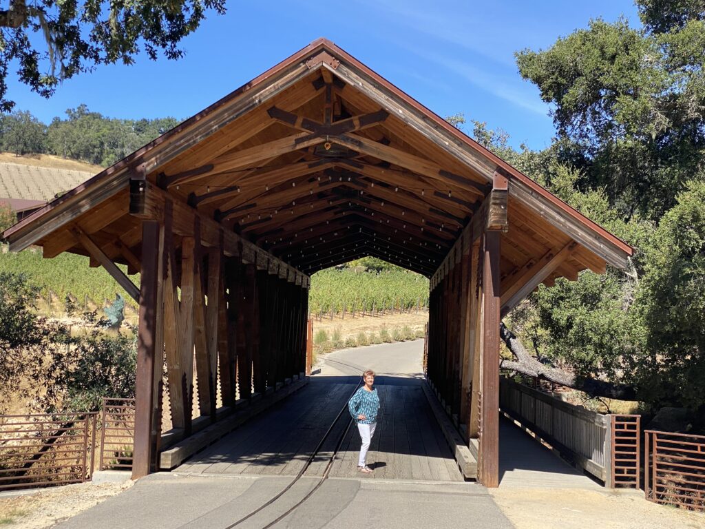 Shelley standing under a covered bridge leading to Halter Ranch Winery and Vineyard