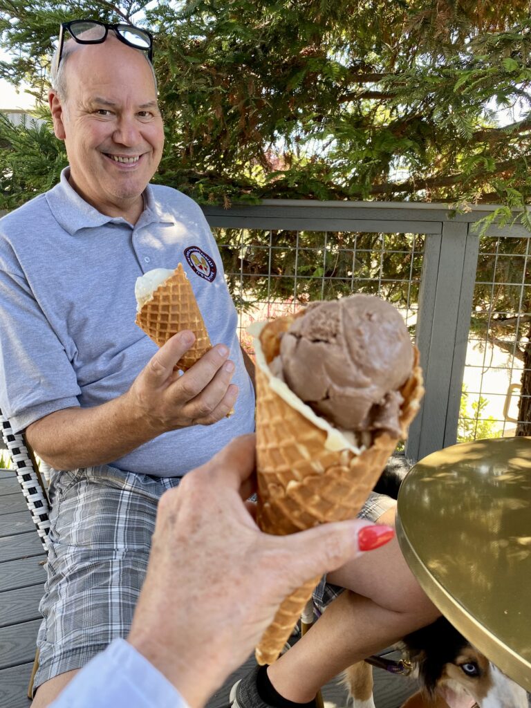 A man holding a waffle cone sheeps milk ice cream and another cone in front