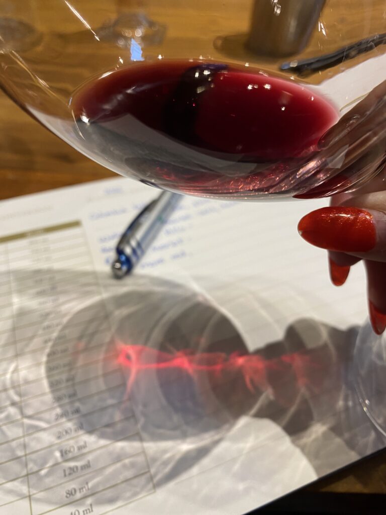 Looking at the color of the merlot by tilting the glass against a white background