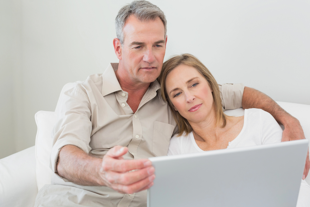 A middle aged couple looking at their laptop considering a reverse home mortgage